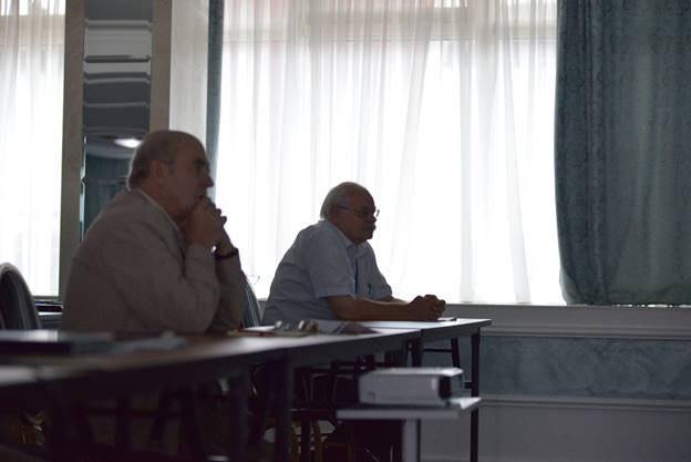 A group of people sitting at a desk in front of a curtain

Description generated with very high confidence