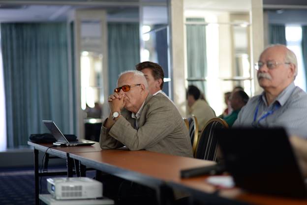 A group of people sitting at a table using a computer

Description generated with very high confidence