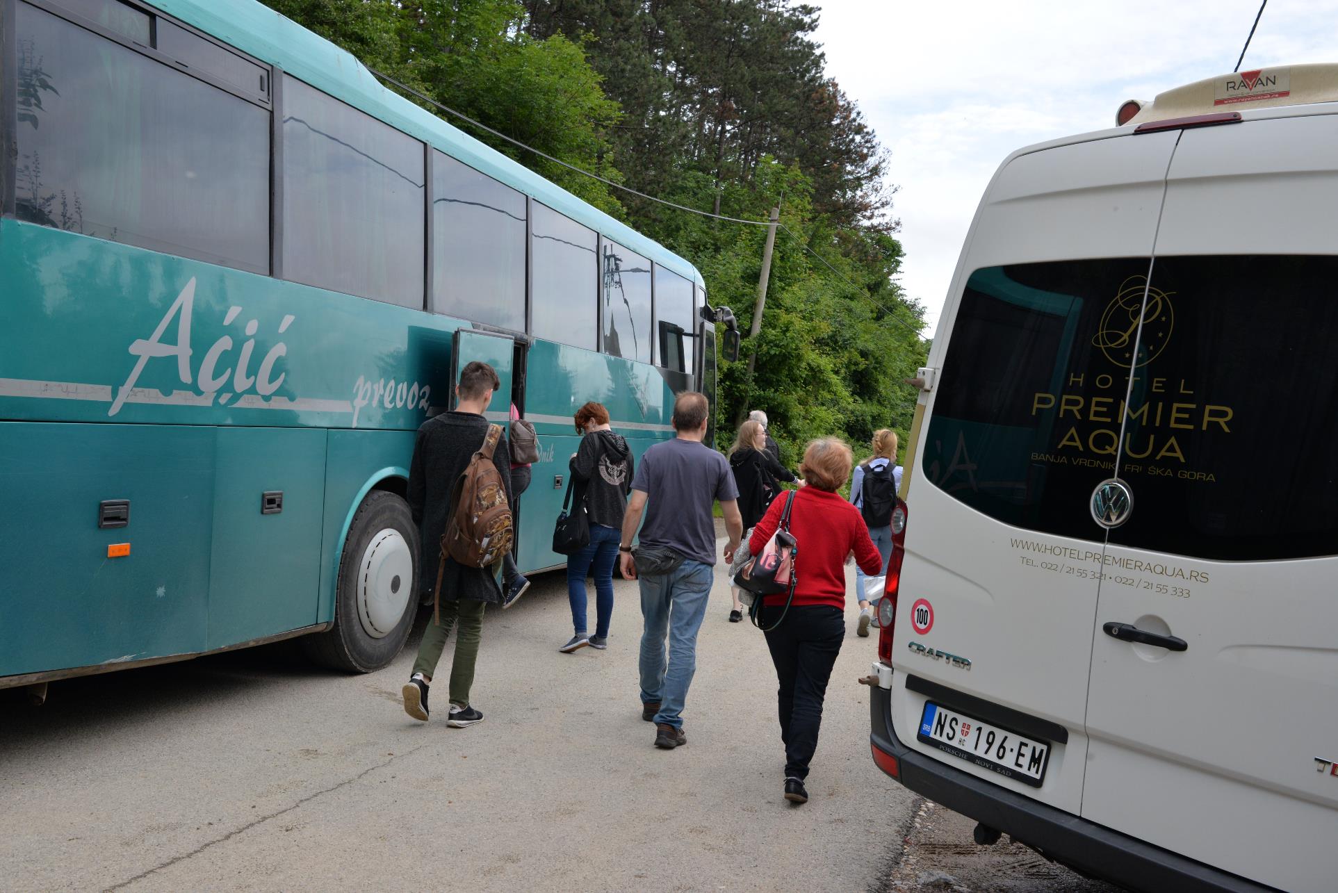 A group of people standing in front of a bus

Description automatically generated