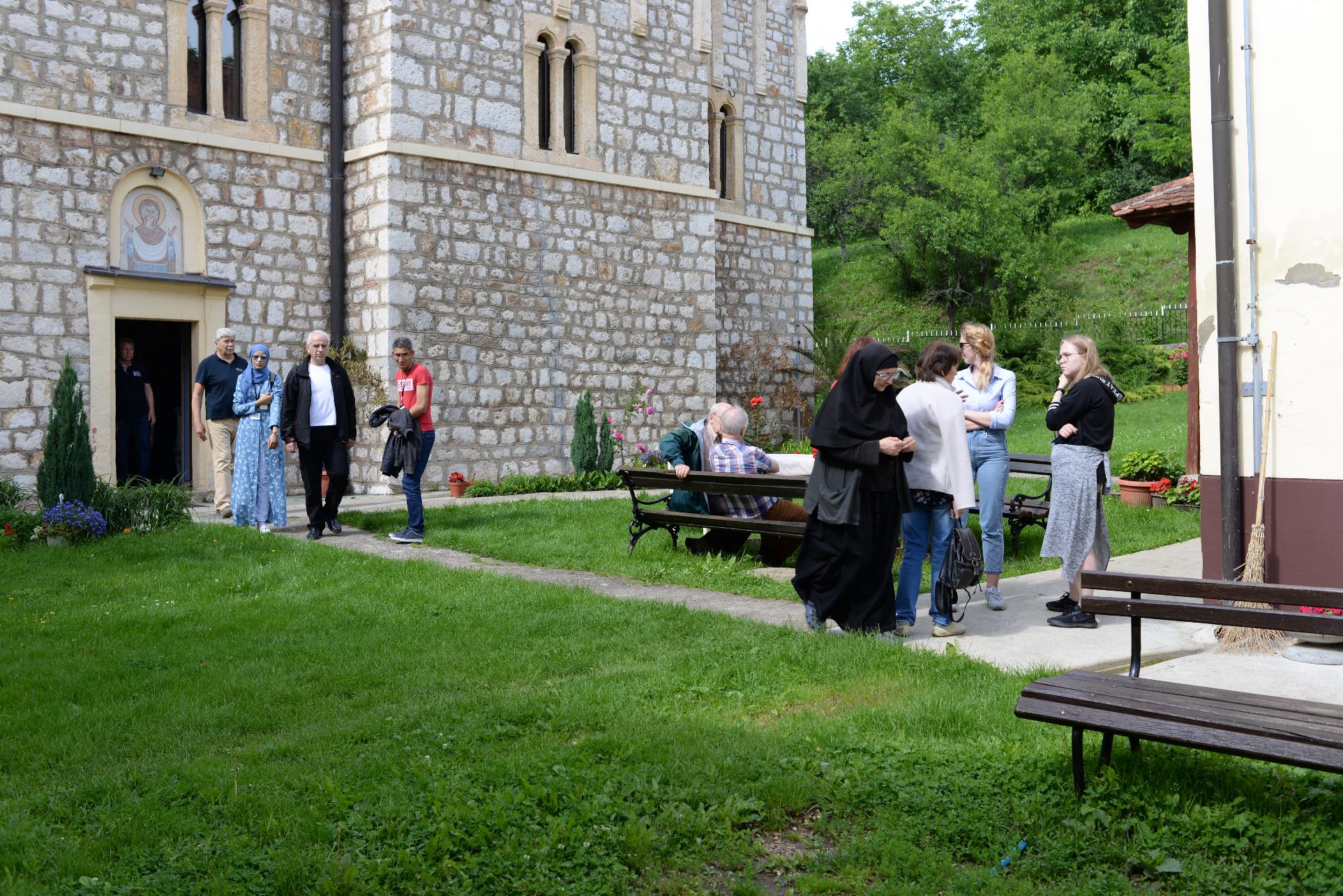 A group of people sitting on a bench in front of a building

Description automatically generated