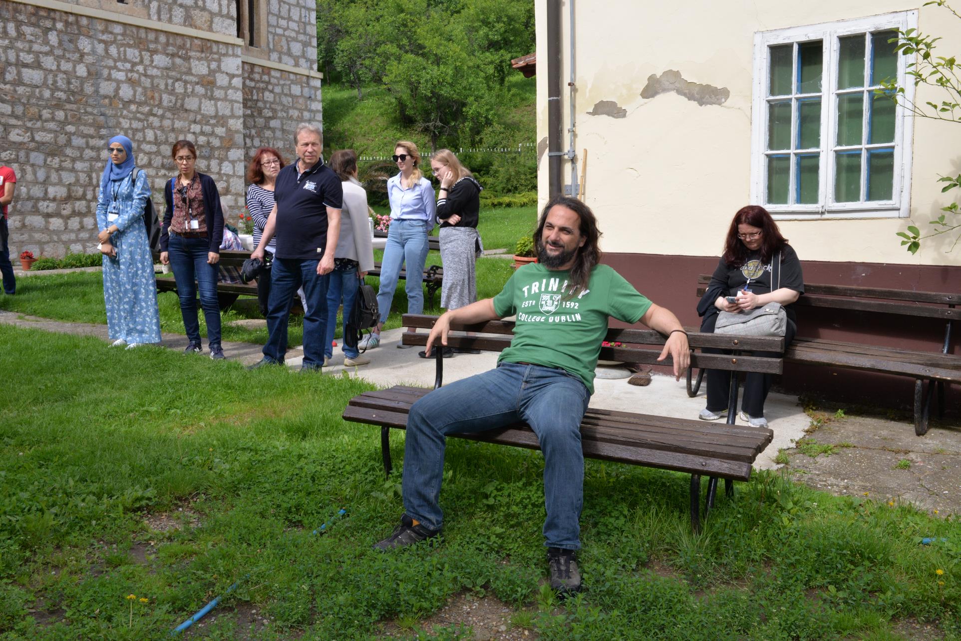 A group of people sitting on a bench in a park

Description automatically generated