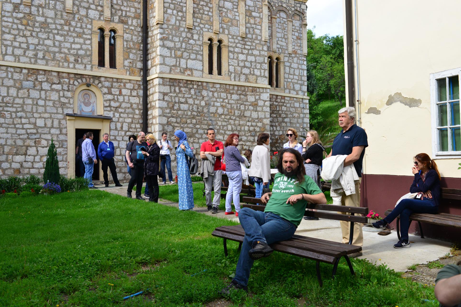 A group of people sitting on a bench in front of a building

Description automatically generated