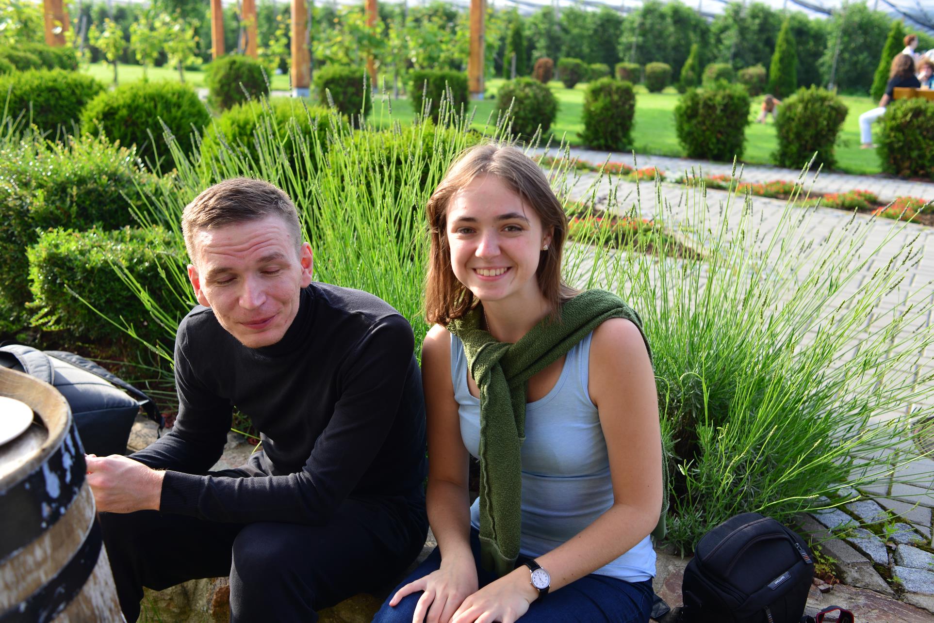 Two people sitting on a bench posing for the camera

Description automatically generated